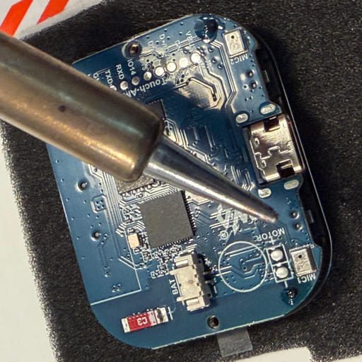 A PitchKallr Watch receiver board on antistatic foam with a soldering iron tip resting on it.